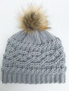 a gray knitted hat with a fur pom - pom on the top