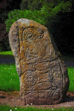 a large stone with carvings on it in the grass