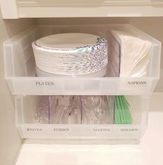 plastic containers are stacked on top of each other in the refrigerator door, holding plates and napkins