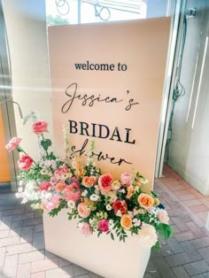 a welcome sign is decorated with flowers and greenery