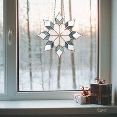 a snowflake hanging from a window sill next to a present on a table