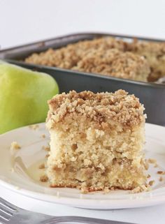 a piece of cake on a plate next to an apple and a pan of apples