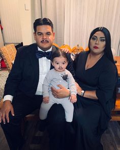 a man in a tuxedo poses with two women and a baby