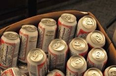 many cans of beer are stacked in a cardboard box