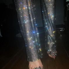 a person's feet in shiny pants and heels with sparkling lights on the leg