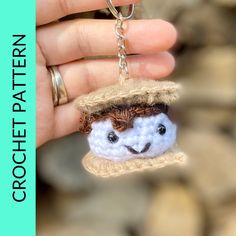 a hand holding a tiny crocheted keychain with a hat on it