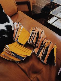 a dog laying on top of a brown couch next to yellow and black pieces of cloth