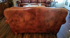 a brown leather couch sitting on top of a hard wood floor