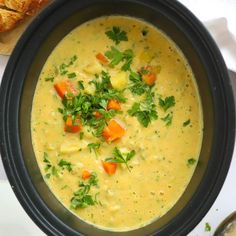 a bowl of soup with bread and parsley on the side is ready to be eaten