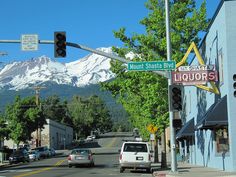 cars are driving down the street in front of a mountain