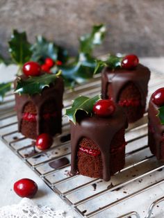 small chocolate cakes with cherries and holly on a cooling rack for holiday desserts