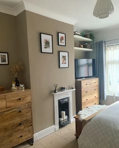 a bedroom with a bed, dresser and television on the wall in front of a window