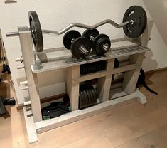 a gym equipment rack with two dumbbells and one barbell on it in a home gym