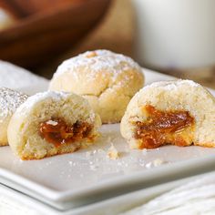 some sugary pastries on a white plate with powdered sugar and jam in the middle