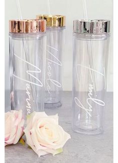 three personalized tumblers with gold lids and pink roses on the table next to each other