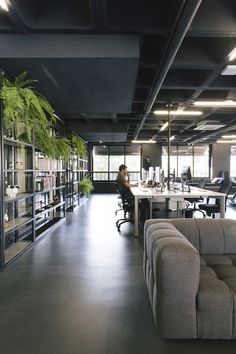 an office with couches, tables and plants in the middle of the room that is empty