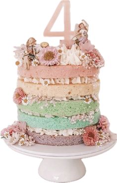 a multi layer cake with flowers and fairy figurines on top is shown in front of the number four