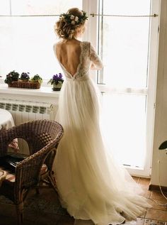 a woman standing in front of a window wearing a dress with flowers on the back