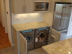 a washer and dryer are in the middle of a kitchen with stainless steel appliances