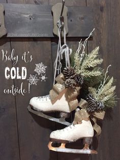 a pair of white ice skates hanging from a wooden wall with pine cones and evergreen branches