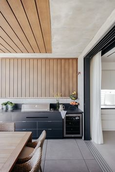 an outdoor kitchen and dining area with wood paneling on the ceiling, along with sliding glass doors leading outside