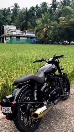 a black motorcycle parked on the side of a road next to a lush green field