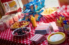 a table topped with lots of food next to a red and white checkered table cloth