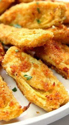 some fried food on a white plate with parmesan cheese and seasoning sprinkles