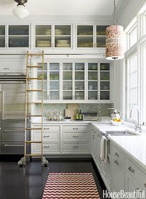 a ladder is in the middle of a kitchen with white cabinets and black flooring