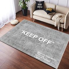 a rug that says keep off on the floor in front of a couch and potted plant