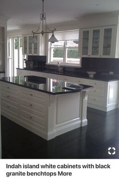 a large kitchen with black counter tops and white cabinets, along with an island in the middle