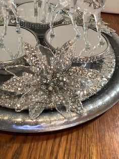 a silver plate topped with candles on top of a wooden table covered in snowflakes