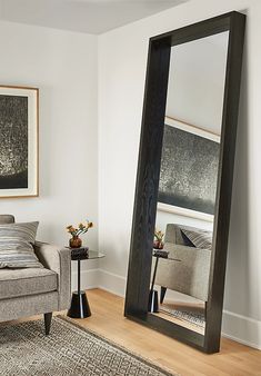 a living room with a couch, chair and large mirror in front of the wall