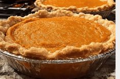 three pies sitting on top of a counter next to each other in pans