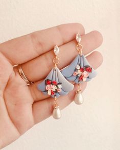 a pair of earrings with flowers and pearls hanging from it's earwires