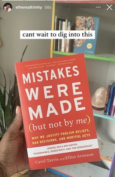 a person holding up a book in front of a bookshelf with the title, what makes we made but not by me?