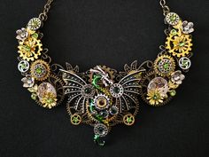 An original, elegant, hand-crafted gift for any Fae, Fantasy, Goth, or Steampunk enthusiast. This hand-crafted bronze filigree articulated necklace is topped with a beautiful, enamelled, green Steampunk dragon.  The dragon is flanked by two genuine clockwork watch mechanisms, Steampunk cogs and gears, and miniature metal flowers.  The design is adorned with miniature emerald-tone diamante rhinestone crystals for a final touch of elegance and sparkle.  This lovely, unique, eye-catching, metal all Steampunk Cogs And Gears, Green Steampunk, Steampunk Cogs, Fantasy Goth, Cogs And Gears, Steampunk Dragon, Steampunk Fantasy, Green Dragon, Bib Necklaces