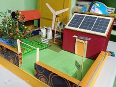 a model of a house with solar panels on the roof and a wind turbine in the background