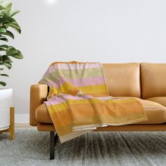 a couch with a blanket on it next to a potted plant