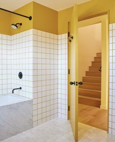 a bathroom with yellow walls and white tiles on the wall, along with a bathtub