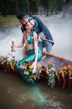 a man and woman are in a boat with flowers on the bottom, holding a candle