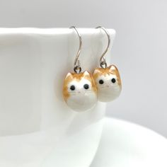 "Product Information Cute and round orange tabbies for any outfit or occasion! Available with Sterling Silver or Gold-Filled ear wires. *I can also make you an all orange tabby cat pair by request. Dimensions Each earring charm is about 3/8\" (0.9 cm) - 1/2\" (1.3 cm) tall. Materials Porcelain Clay Underglaze Colors Mid-Fire Clear Glaze Sterling Silver / Gold-Filled Ear Wires Care Instructions While porcelain clay is durable, it is not shatter-proof. Please wear and handle with care!  Earrings m Clay Underglaze, Earrings Ceramic, Orange Tabby Cats, Orange Tabby, Porcelain Clay, Cat Jewelry, Cat Lover Gift, Gift Cute, Cat Earrings