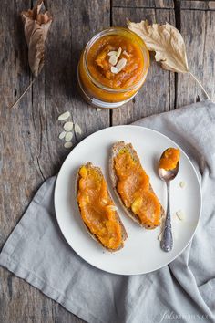 two pieces of bread sitting on top of a white plate next to a jar of peanut butter