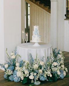 a white and blue wedding cake sitting on top of a table next to some flowers