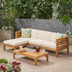 a wooden couch sitting on top of a stone floor next to a table and potted plants