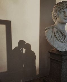 the shadow of two people standing next to a bust of a roman man and woman