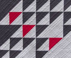 a black and white quilt with red diagonals on the top, along with an orange triangle at the bottom