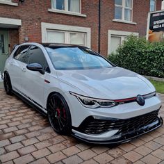 a white car parked in front of a brick building