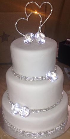 a three tiered wedding cake with two hearts on the top and diamonds on the bottom