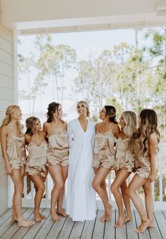 a group of women standing next to each other on a wooden floor with one woman in a white dress